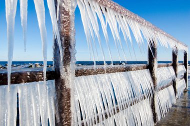Güneşli bir günde, karla kaplı eski, paslı iskele. Buz parçaları yakın plan. Baltık Denizi, Letonya