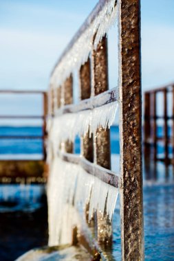 Güneşli bir günde, karla kaplı eski, paslı iskele. Buz parçaları yakın plan. Baltık Denizi, Letonya