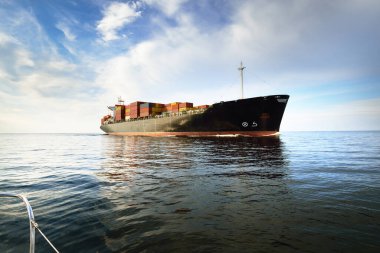 Norfolk limanından ayrılan büyük bir yük konteynırı gemisi, yakın plan. Bulutlu mavi gökyüzü. Virginia, ABD