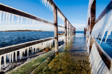 Güneşli bir günde, karla kaplı eski, paslı iskele. Buz parçaları yakın plan. Baltık Denizi, Letonya