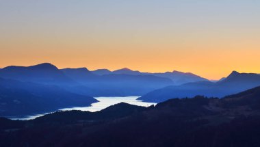 Gün batımında Fransız Alpleri 'ndeki dağ gölü Lac de Serre-poncon' un panoramik manzarası. Temiz gökyüzü, altın ışık, durgun su. Seyahat yerleri, turizm, dönüm noktası, doğa, Fransa 'da Noel tatilleri