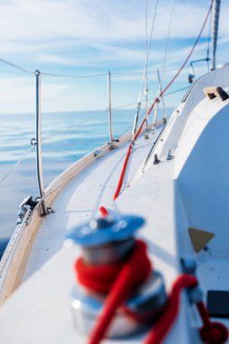 Açık bir Baltık Denizi 'nde güneşli bir günde beyaz bir yat sürüyor. Güverteden pruvaya bir manzara, yakın plan kırmızı vinç. Estonya