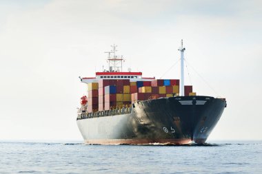 Norfolk limanından ayrılan büyük bir yük konteynırı gemisi, yakın plan. Bulutlu mavi gökyüzü. Virginia, ABD