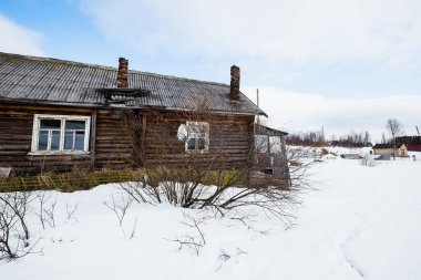 Geleneksel, yalnız, ahşap bir ev. Kandalaksha Körfezi kıyıları, karla kaplı dağlar ve arka planda Kola Yarımadası 'nın ormanları. Beyaz Deniz, Kutup Dairesi, Karelya, Rusya