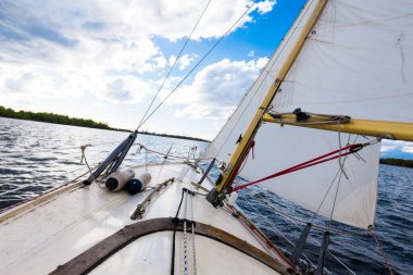 Açık bir günde beyaz bir yat gezintisi. Güverteden pruvaya ve yelkenlere bir manzara. Dalgalar ve su sıçramaları. Baltık Denizi, Letonya