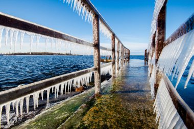 Güneşli bir günde, karla kaplı eski, paslı iskele. Buz parçaları yakın plan. Baltık Denizi, Letonya
