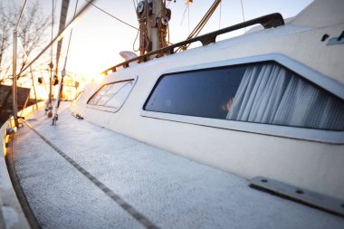 Karla kaplı beyaz yatın güvertesine yakın plan. Kış batımı. Riga, Letonya