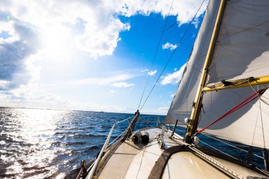 Açık bir günde yelkenli dolu bir yat. Güverteden pruvaya ve yelkenlere bir manzara. Dalgalar ve su sıçramaları. Baltık Denizi, Letonya