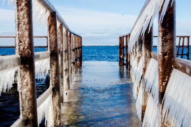 Güneşli bir günde, karla kaplı eski, paslı iskele. Buz parçaları yakın plan. Baltık Denizi, Letonya