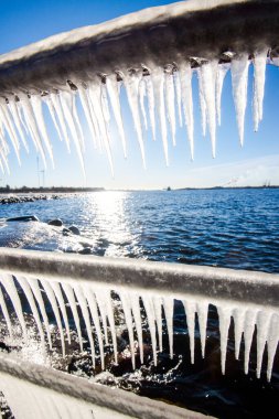 Güneşli bir günde, karla kaplı eski, paslı iskele. Buz parçaları yakın plan. Baltık Denizi, Letonya