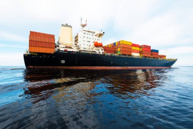 Norfolk limanından ayrılan büyük bir yük konteynırı gemisi, yakın plan. Bulutlu mavi gökyüzü. Virginia, ABD