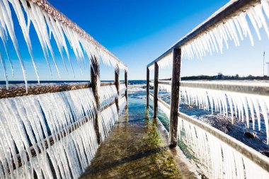 Güneşli bir günde, karla kaplı eski, paslı iskele. Buz parçaları yakın plan. Baltık Denizi, Letonya