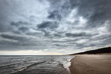 Baharda Baltık Denizi 'nin kumlu kıyılarında fırtına bulutları, dramatik gökyüzü, dalgalar ve su sıçramaları. Koyu deniz manzarası. - Letonya. Hava, iklim değişikliği, ekoloji, çevre, doğa