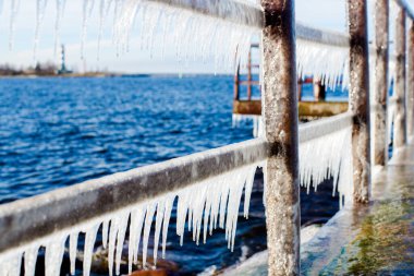 Güneşli bir günde, karla kaplı eski, paslı iskele. Buz parçaları yakın plan. Baltık Denizi, Letonya