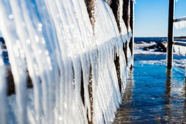Güneşli bir günde, karla kaplı eski, paslı iskele. Buz parçaları yakın plan. Baltık Denizi, Letonya