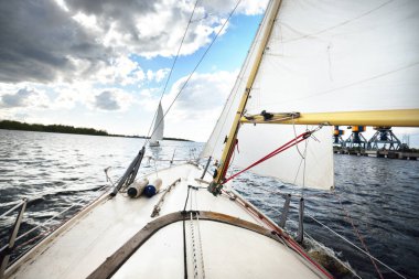 Açık bir günde yelkenli dolu bir yat. Güverteden pruvaya ve yelkenlere bir manzara. Dalgalar ve su sıçramaları. Baltık Denizi, Letonya