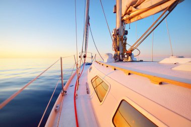 Sakin su. Beyaz yat gün batımında denize açılacak. Güverteden pruvaya, direğe ve yelkenlere bir manzara. Baltık Denizi, Letonya