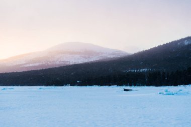 Gün batımında kar fırtınasından sonra Kandalaksha koyunda. Tahta tekne, yakın plan. Altın akşam bulutları. Arka planda Kola Yarımadası 'nın dağları ve kozalaklı ormanları var. Beyaz deniz, Kutup dairesi, Karelia, Rusya