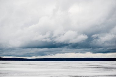 Kış manzarası. Donmuş karla kaplı göl manzarası. Arka planda orman var. Fırtınalı akşam bulutları. Onega Gölü, Karelia, Rusya