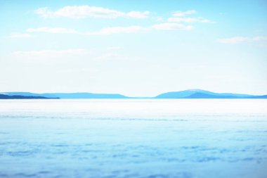 Donmuş gölün panoramik manzarası. Arka planda karla kaplı dağlar ve kozalaklı ormanlar var. Açık mavi gökyüzü. Kola Yarımadası, Murmansk bölgesi, Kutup Dairesi, Karelia, Rusya