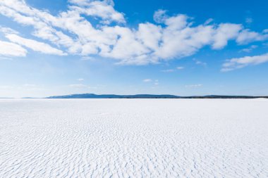 Donmuş gölün panoramik manzarası. Arka planda karla kaplı dağlar ve kozalaklı ormanlar var. Açık mavi gökyüzü. Kola Yarımadası, Murmansk bölgesi, Kutup Dairesi, Karelia, Rusya