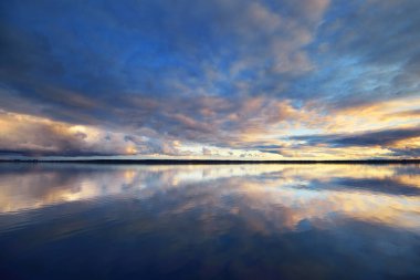 Finlandiya Körfezi, gün batımında, Hanko Yarımadası. Parlayan renkli bulutları olan dramatik gökyüzü, suda simetri yansımaları, doğal ayna. Panoramik manzara. Destansı bulut manzarası. Doğa, çevre, ekoloji