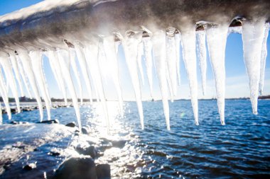 Güneşli bir günde, karla kaplı eski, paslı iskele. Buz parçaları yakın plan. Baltık Denizi, Letonya