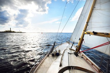 Açık bir günde yelkenli dolu bir yat. Güverteden pruvaya ve yelkenlere bir manzara. Dalgalar ve su sıçramaları. Baltık Denizi, Letonya