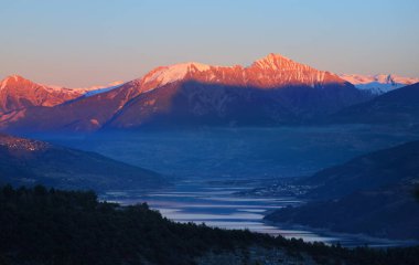 Gün batımında Fransız Alpleri 'ndeki dağ gölü Lac de Serre-poncon' un panoramik manzarası. Temiz gökyüzü, altın ışık, durgun su. Seyahat yerleri, turizm, dönüm noktası, doğa, Fransa 'da Noel tatilleri