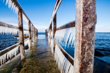 Güneşli bir günde, karla kaplı eski, paslı iskele. Buz parçaları yakın plan. Baltık Denizi, Letonya