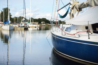Açık bir yaz gününde, yakın planda mavi bir yat iskeleye demirlemiş. Riga Limanı, Daugava Nehri, Letonya