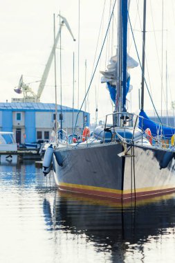 Açık bir yaz gününde açık bir rıhtıma demirlenmiş mavi şalopeli yat, yakın çekim. Arka planda tekneler var. Riga Limanı, Letonya
