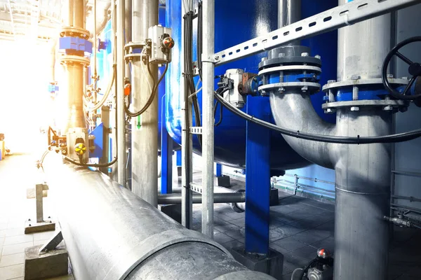 Large industrial water treatment and boiler room. Shiny steel metal pipes, pumps, valves. Industry, technology, special equipment, biotechnology, chemistry, ecology, heating, workplace safety