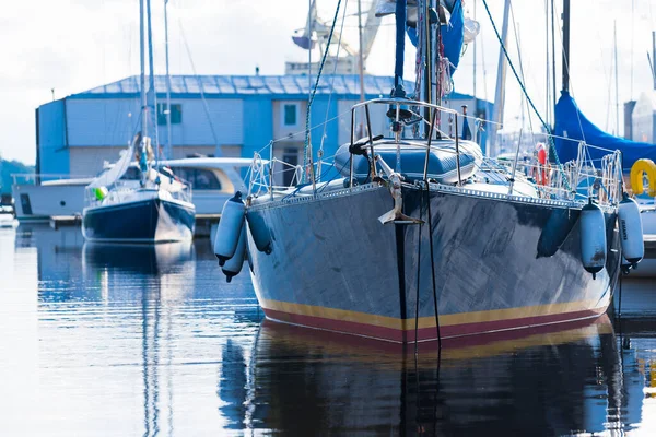 Açık bir yaz gününde açık bir rıhtıma demirlenmiş mavi şalopeli yat, yakın çekim. Arka planda tekneler var. Riga Limanı, Letonya