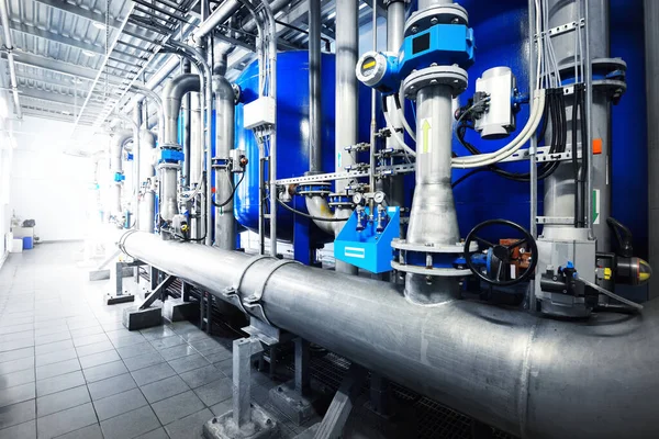 Large industrial water treatment and boiler room. Shiny steel metal pipes, pumps, valves. Industry, technology, special equipment, biotechnology, chemistry, ecology, heating, workplace safety