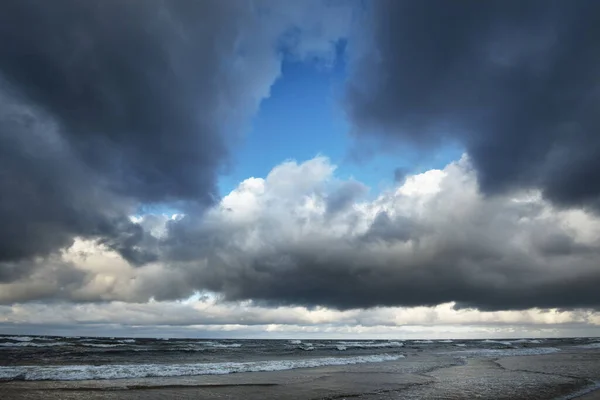 Autumn. Storm clouds above the sea. Waves and water splashes. Warm evening sunlight. Baltic sea, Garciems, Latvia