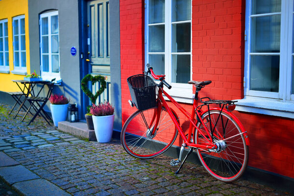 A red bicycle parked near the old brick house, a view of the empty street in a quarantine zone. People are staying home because of virus outbreak. Copenhagen, Denmark
