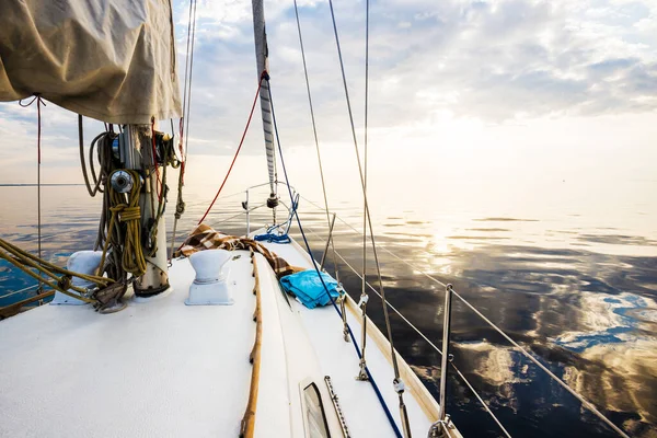 白いヨットは日没時に静かな水の中を航海する デッキから弓 マスト 帆への眺め 見事な雲景だ 自然鏡だ スポーツとレクリエーションのテーマ バルト海 ラトビア — ストック写真