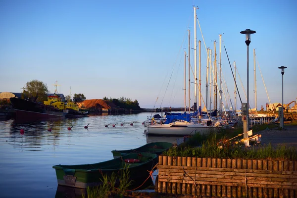 A view of a small yacht marina at sunset. Yachts and fishing boats close-up. Clear blue sky. Port of Mersrags, Latvia