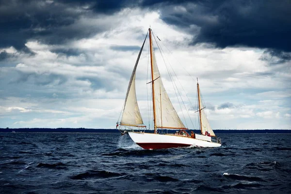 風の強い日に海岸に対して波の上を航海する古い木製の2つのマストヨット — ストック写真