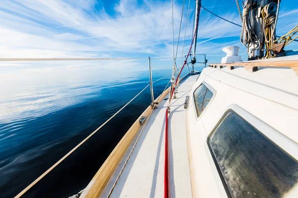 White sloop rigged yacht sailing in an open Baltic sea on a clear sunny day. A view from the deck to the bow, mast and sails. Estonia