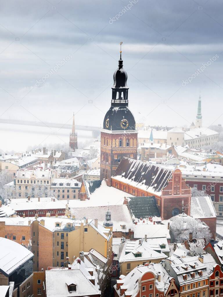 Panoramic aerial view of the Riga old town and Daugava river from St. Peter's Church on a clear winter day. Morning fog and snow-covered houses. Latvia