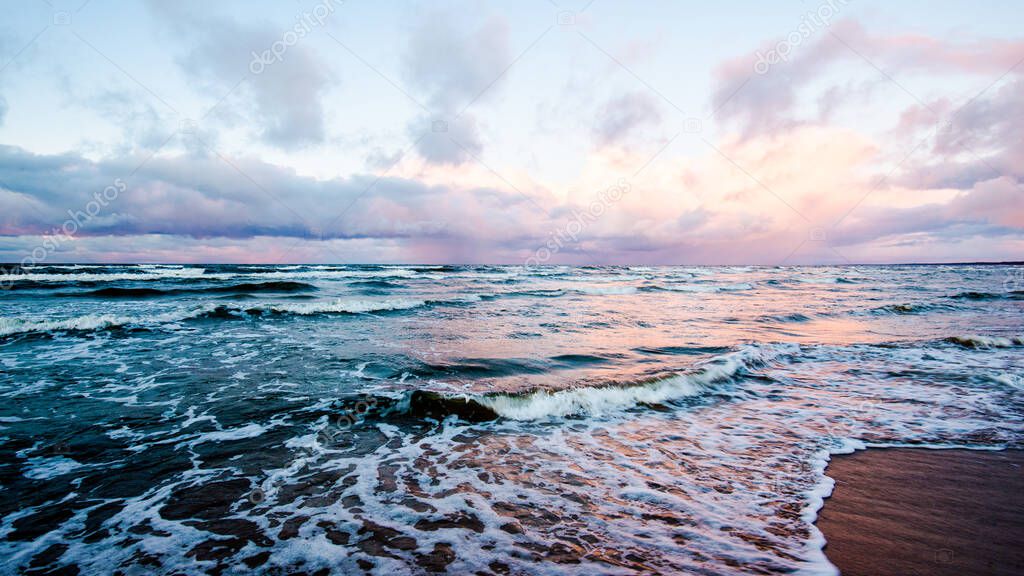 Colorful winter sunset. Cold stormy waves and clouds over the Baltic sea, Latvia