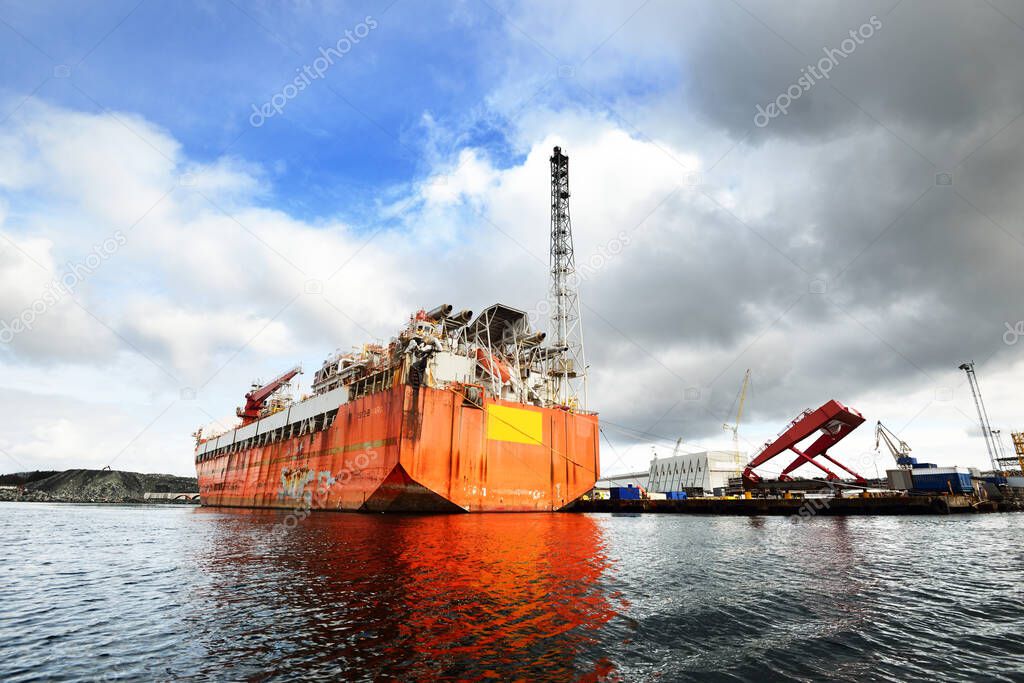 Floating, production, storage and offloading FPSO vessel moored to the shore in a port, close-up. Riga, Latvia. Fuel and power generation, industry, global communications, environmental damage