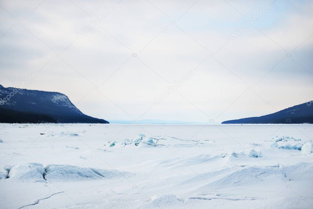 Ice pressure ridge of Kandalaksha bay under a storm sky. Colorful evening clouds. Mountains and coniferous forests of Kola Peninsula in the background. White sea, Polar circle, Karelia, Russia