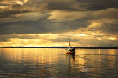 Gün batımında yelkenli tekneyle açılacak. Renkli, parıldayan altın akşam bulutları. Destansı bulut manzarası. Sudaki simetri yansımaları, doğal ayna. Hanko Yarımadası, Finlandiya Körfezi
