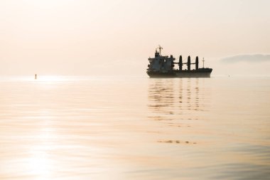 Gün batımında büyük bir yük vinci gemisi. Akşam bulutları ve parlak güneş ışığı. Baltık Denizi, Letonya