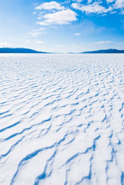 Donmuş gölün panoramik manzarası. Arka planda karla kaplı dağlar ve kozalaklı ormanlar var. Açık mavi gökyüzü. Kola Yarımadası, Murmansk bölgesi, Kutup Dairesi, Karelia, Rusya
