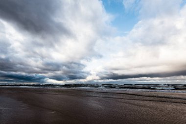 Sonbahar. Denizin üstünde fırtına bulutları. Dalgalar ve su sıçramaları. Sıcak akşam güneşi. Baltık Denizi, Garciems, Letonya