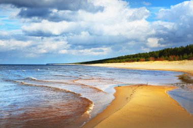 Güneşli bir bahar gününde, Baltık Denizi 'nin kristal berrak suları ve kumlu kıyıları. Sığ su. Dramatik bulut manzarası. - Letonya. Mevsimler, iklim değişikliği, hava durumu